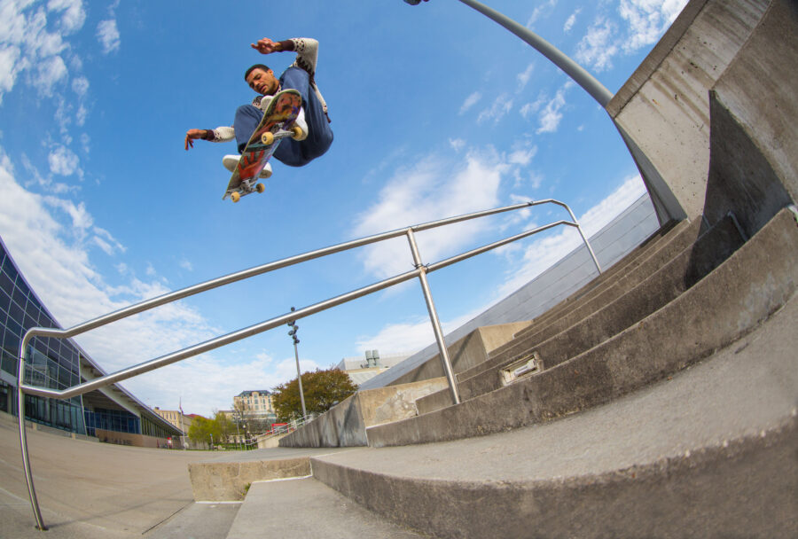 Justin Henry frontside kickflips over a rail backdropped by a clear blue sky in his hometown of Columbus, Ohio. Photo by Mike Chinner.