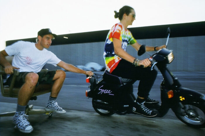 Mark Lewman being towed by a moped whilst sat on a swivel chair.
