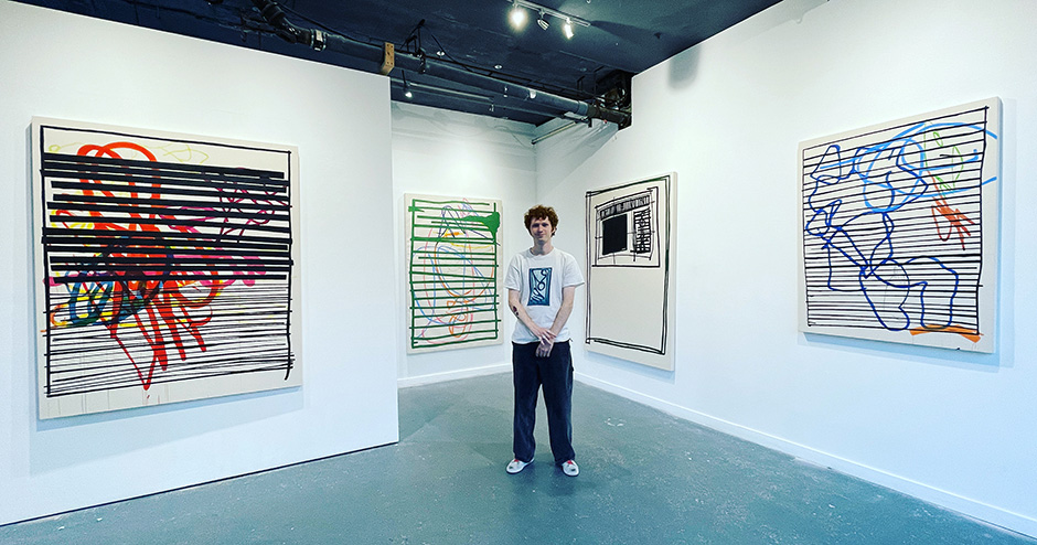 Tygar Smith in front of some of his larger scale paintings at his 'Redacted' show